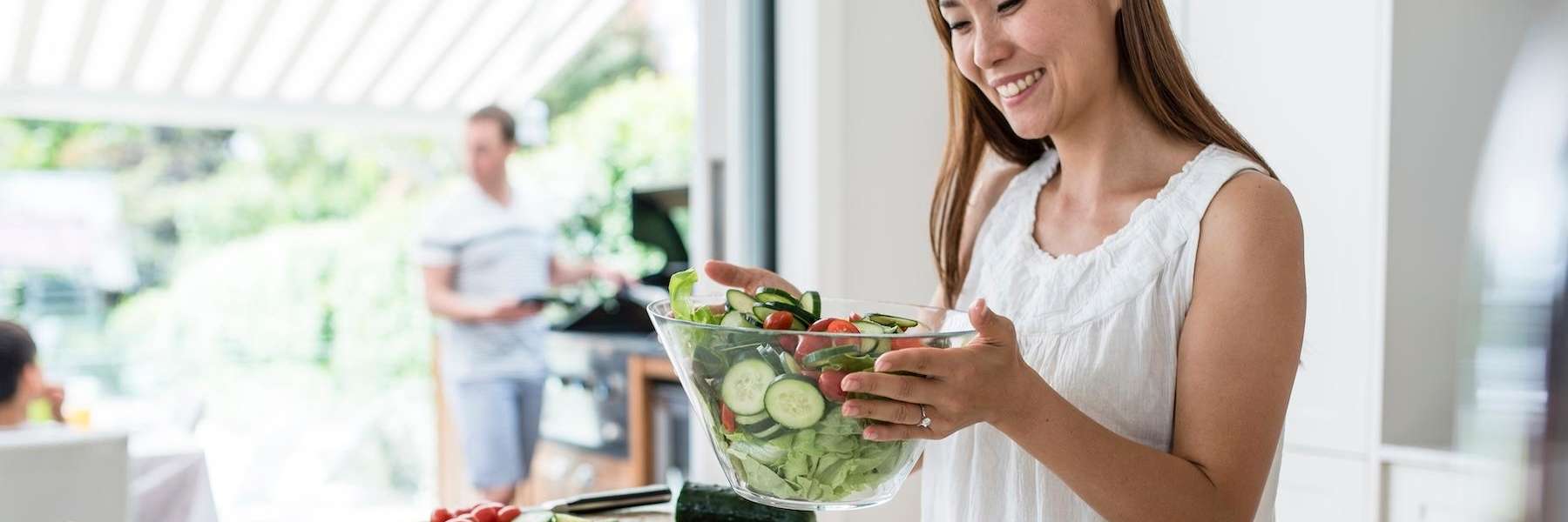 Smiling woman preparing a fresh salad at home promoting healthy eating and wellness in West Covina C