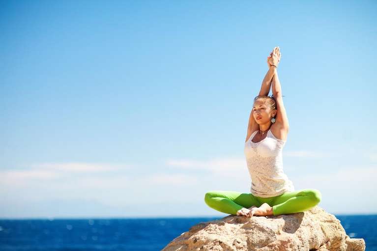Woman practicing outdoor yoga by the ocean promoting healthy living and wellness in West Covina CA